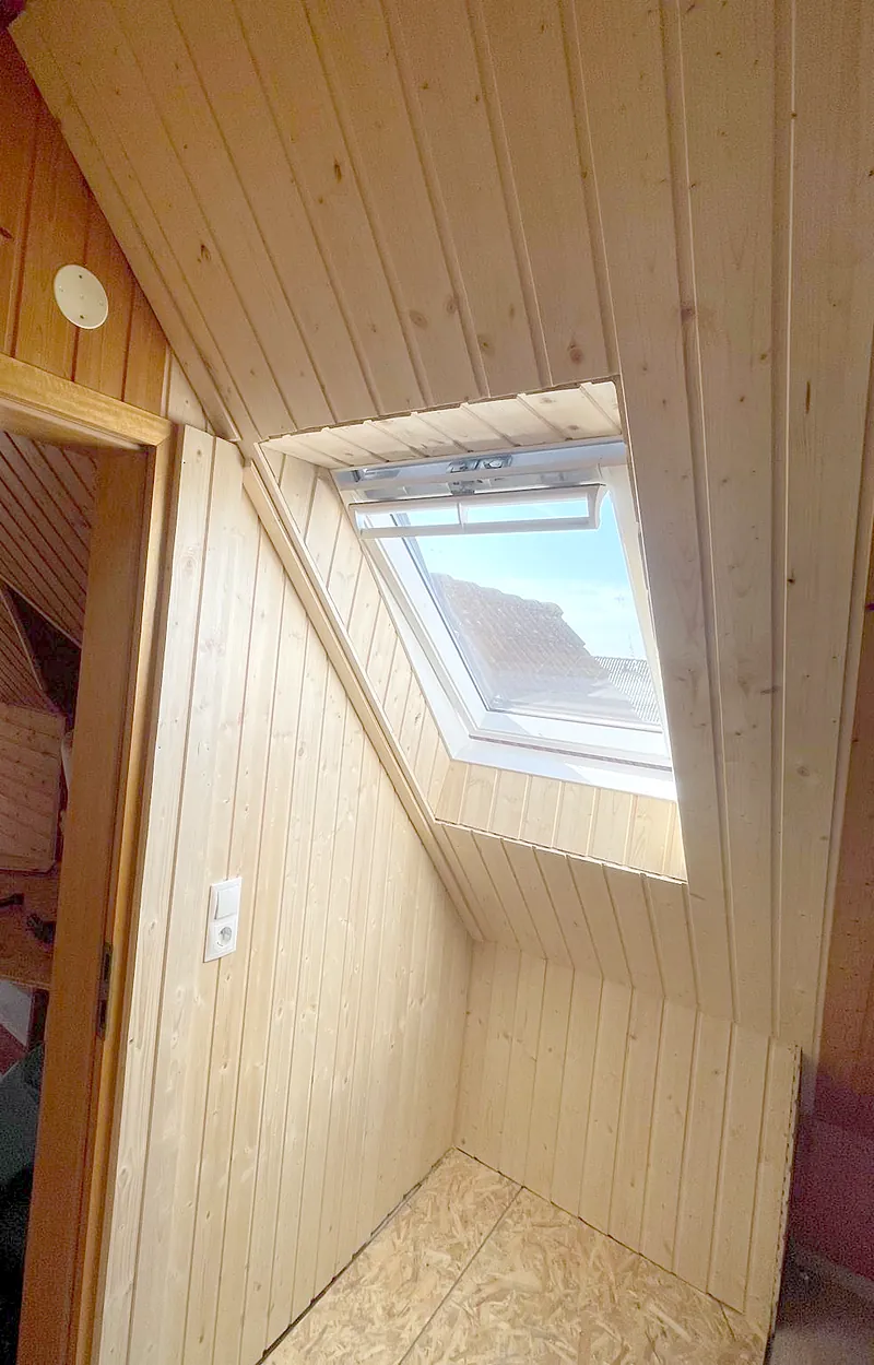 Dachgeschoss mit Holzverkleidung und Dachfenster.