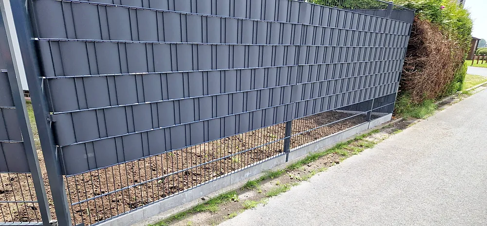 Doppelstabmattenzaun mit Sichtschutzstreifen an einem Weg.